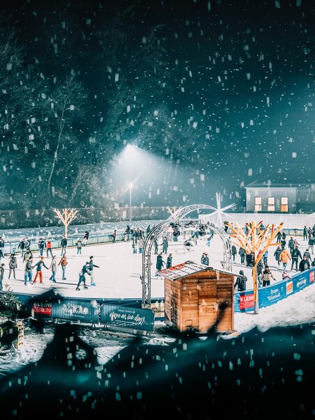 Winter scene at the ice skating rink in Graz, featuring numerous skaters and festive lights. | © Stefan Leitner