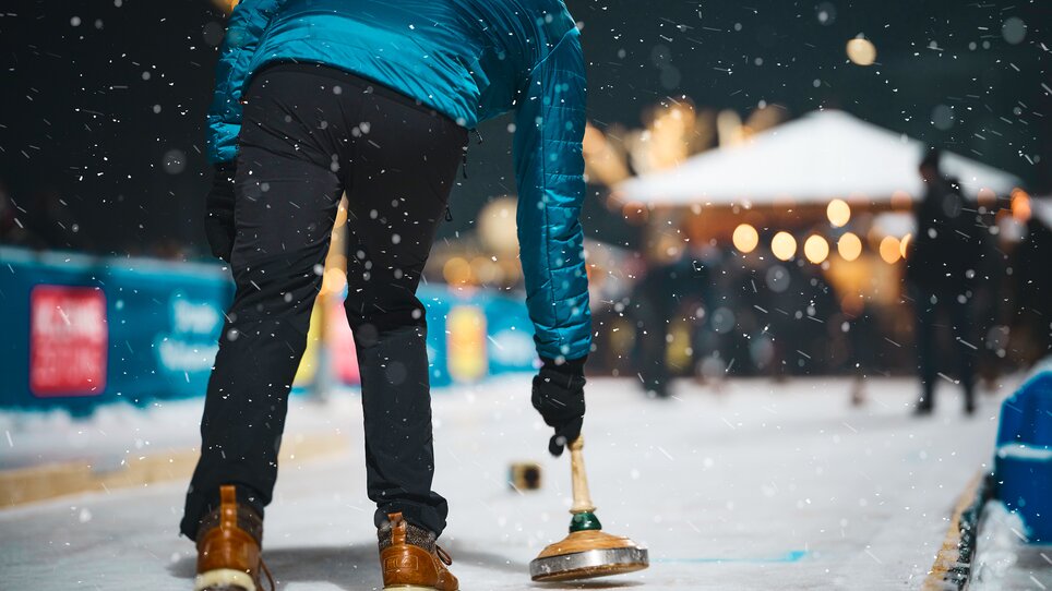 A curling player on a festively decorated ice skating rink. | © Stefan Leitner