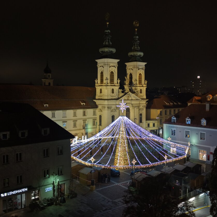Overview of Mariahilferplatz in Graz with a lit Christmas tree and historic buildings. | © Easy Conceptz GmbH