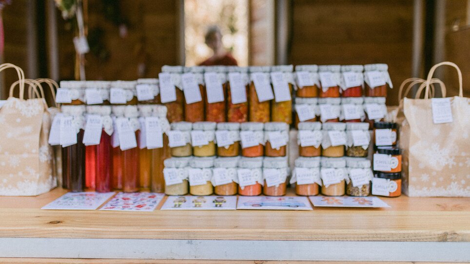 Un banco con vari prodotti conservati in barattoli e sacchetti regalo. | © Evgenia Rieger Photography