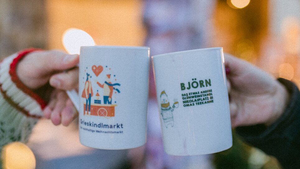 Due persone bevono bicchieri al Grieskindlmarkt di Nikolaiplatz a Graz. | © Evgenia Rieger Photography