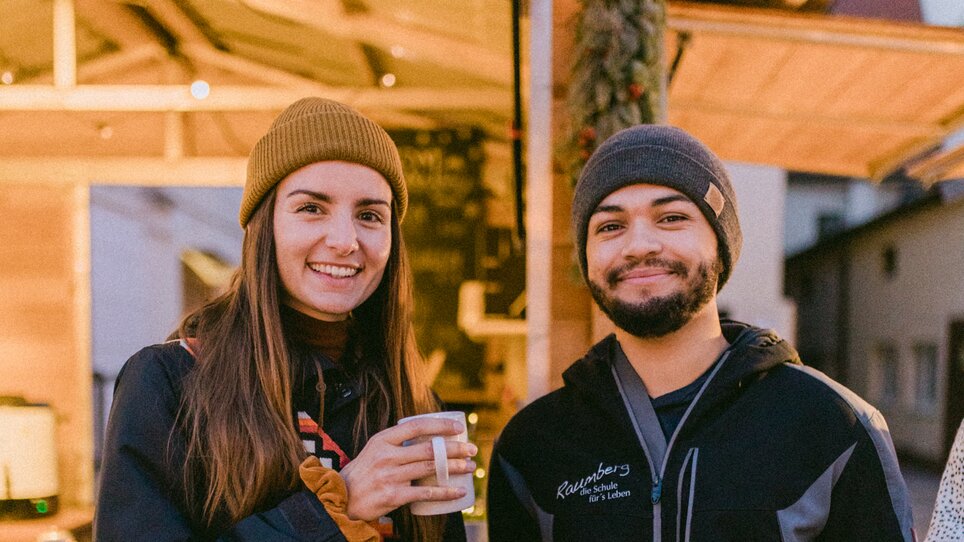 Una coppia in abbigliamento invernale tiene delle tazze in un ambiente illuminato. | © Evgenia Rieger Photography