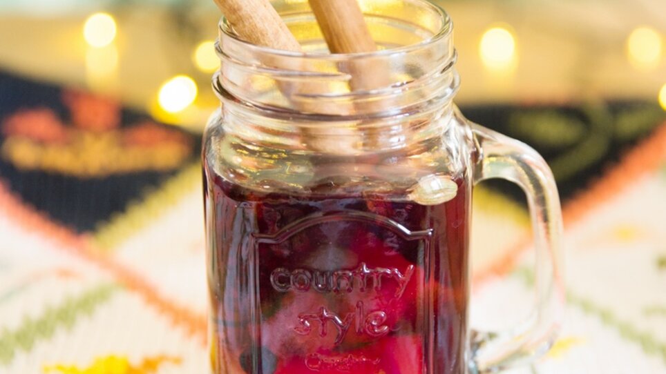 A glass of punch, garnished with cinnamon sticks and star anise, with atmospheric lights in the background. | © Evgenia Rieger Photography