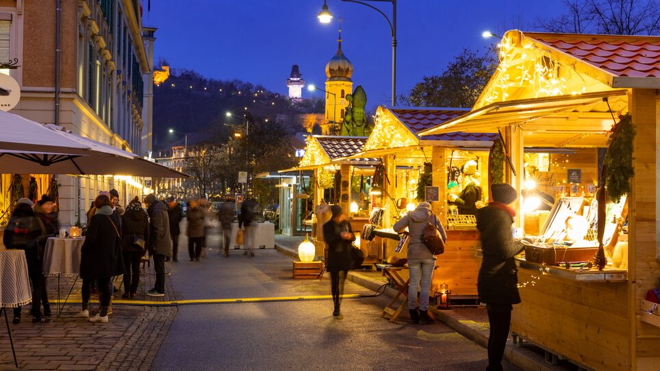 Bancarelle illuminate al mercatino di Natale a Graz di notte. | © Graz Tourismus - Harry Schiffer