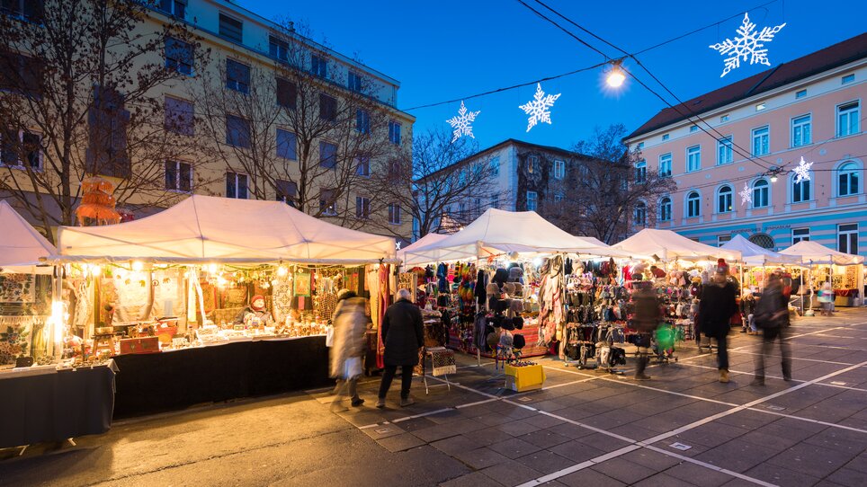 Colorful market stalls with lights and goods in Graz at Tummelplatz. | © Graz Tourismus - Harry Schiffer