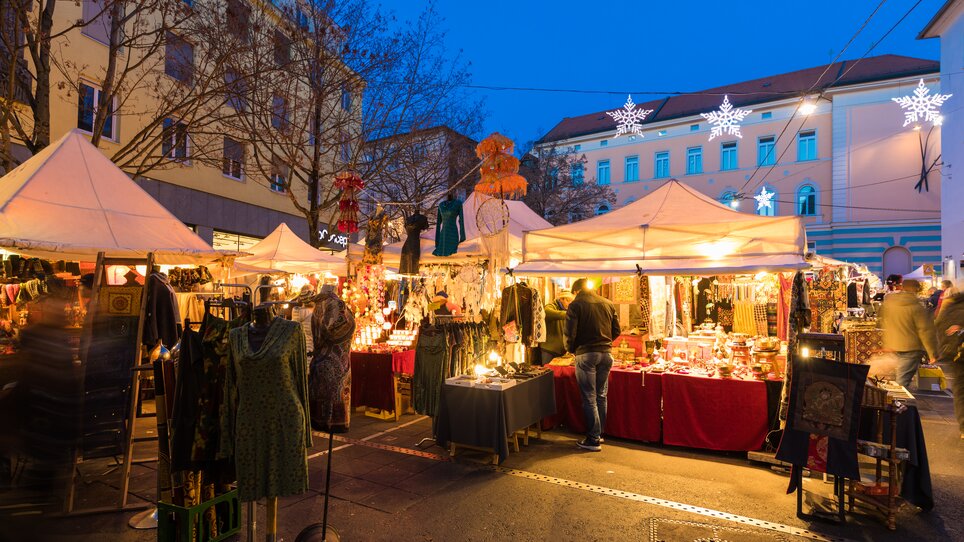 Christmas market in Graz featuring stalls, lights, and visitors. | © Graz Tourismus - Harry Schiffer