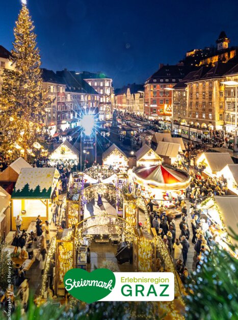 Weihnachtsmarkt in Graz mit Blick auf den Grazer Uhrturm und die festlich beleuchtete Stadt.