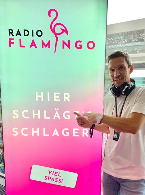 A man with headphones points to a Radio Flamingo sign. | © Radio Flamingo