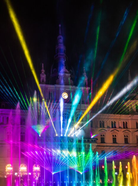 Colorful light show in front of Graz Town Hall with water features. | © Graz Tourismus - Harry Schiffer