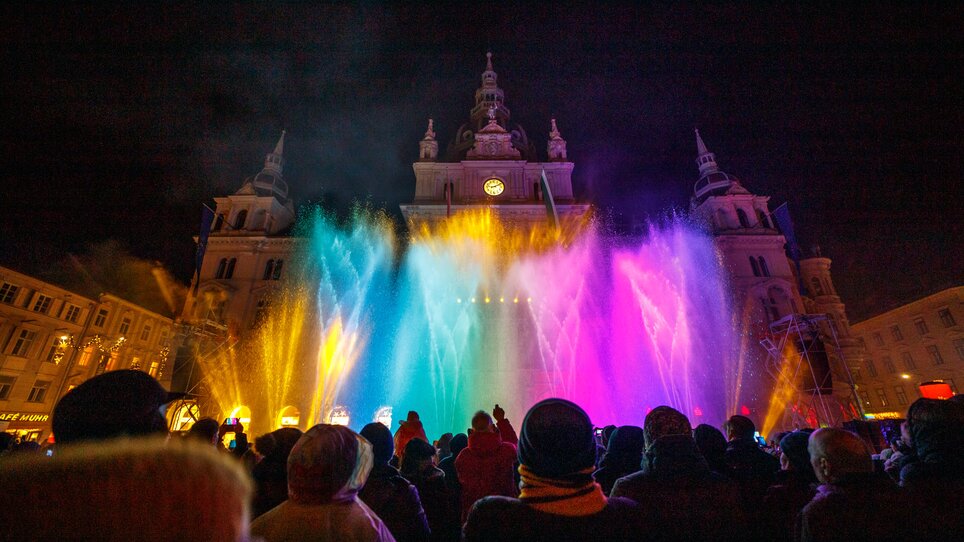 Menschen schauen eine bunte Wasser- und Lichtshow am Hauptplatz von Graz. | © Ivents-Kulturagentur - Erwin Scheriau
