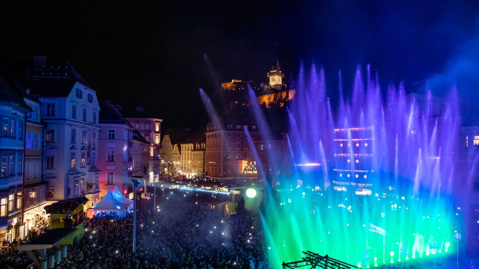 Beleuchtete Wasserfontänen in Graz während des Silvester-Spektakels, im Hintergrund der Grazer Uhrturm. | © Ivents-Kulturagentur - Erwin Scheriau