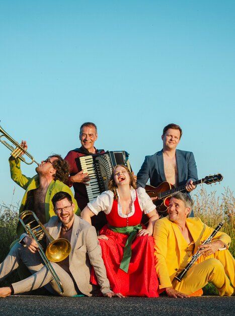 six musicians in colourful dresses are posing with their instruments | © Astrid Bartl