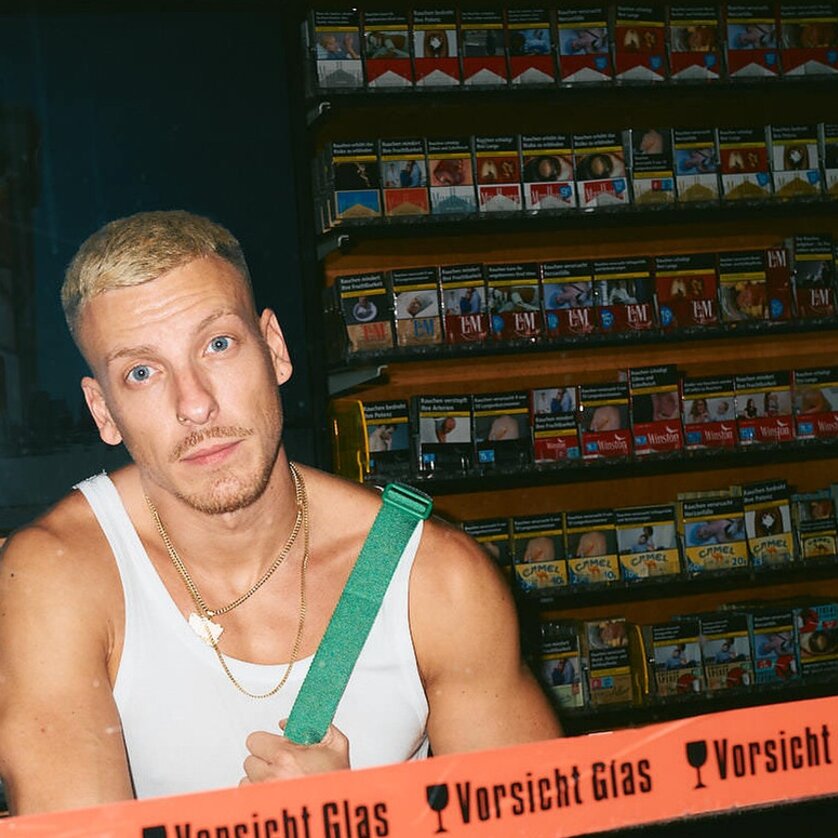 ein junger Mann in Unterhemd steht hinter der Verkaufstheke einer Trafik | © Marvin Ruppert