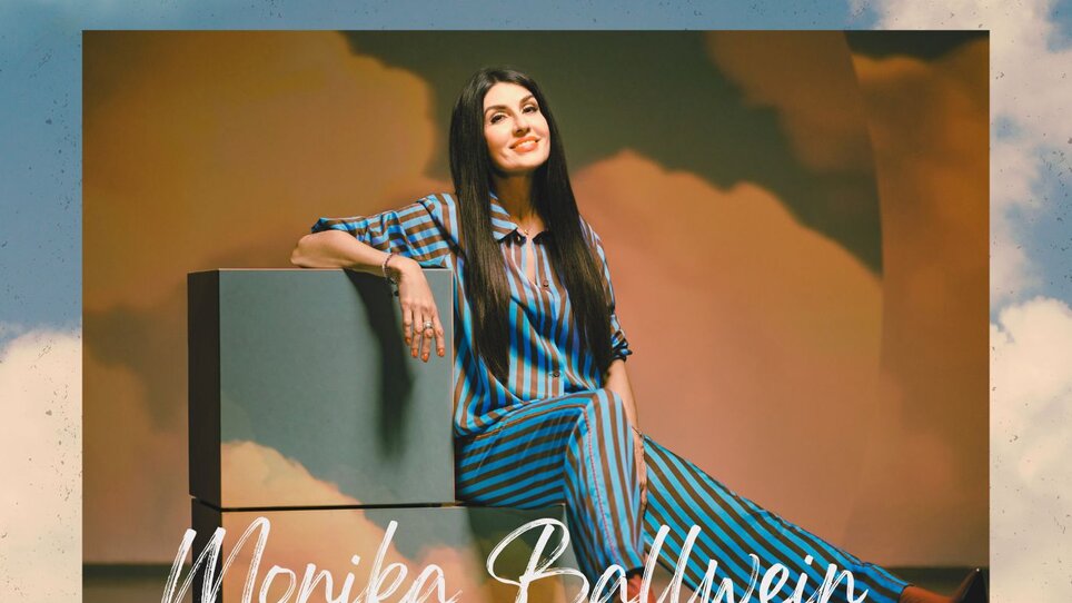 Monika Ballwein poses in striped outfit for her album "WIE DU".