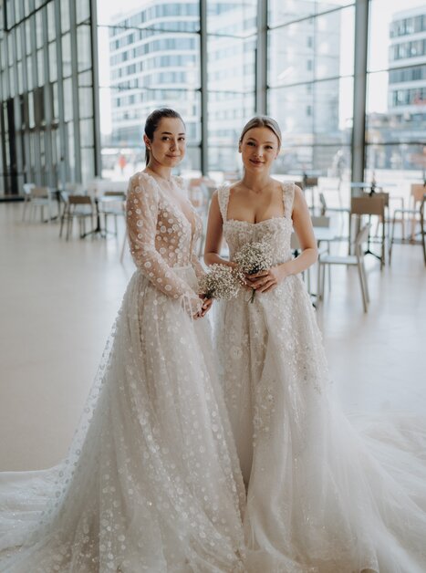 zwei junge Frauen tragen romantische Brautkleider | © THE CLICK Wedding