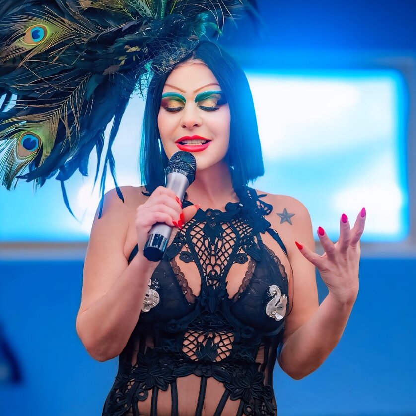 Eine performende Person mit Mikrofon und auffälligem Outfit. | © Bernhard Schinder