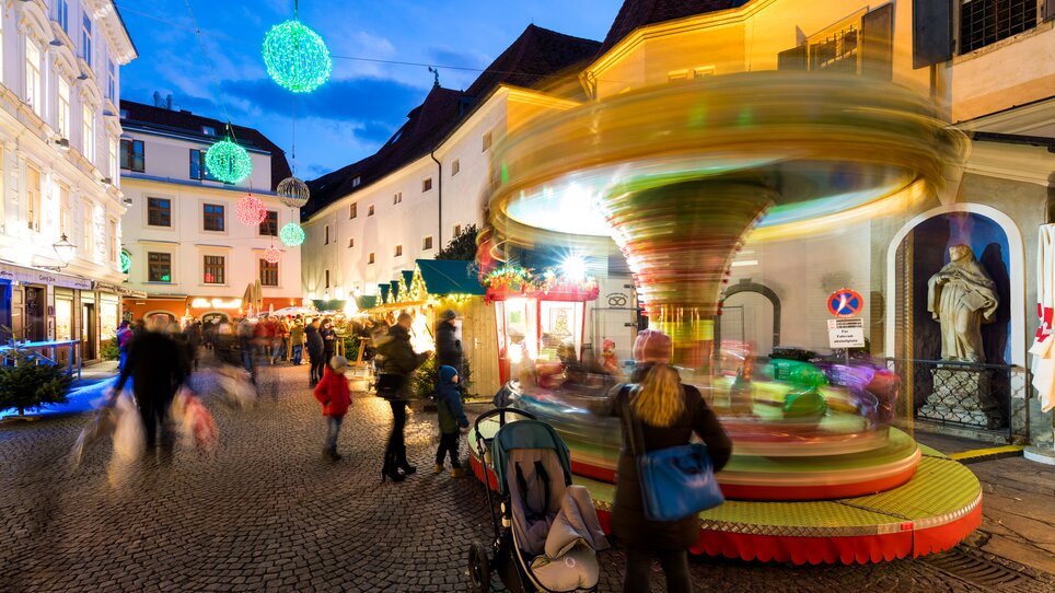 Lively scene with carousel and Christmas stalls in Graz's Franziskanerviertel. | © Graz Tourismus - Harry Schiffer