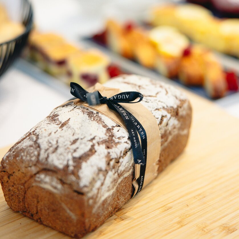Delizioso brunch all'Augarthenhotel di Graz | © Augartenhotel x einsnullneun Una pagnotta di pane marrone decorata con un fiocco e il logo dell'Augarten Art Hotel | © Augartenhotel x einsnullneun