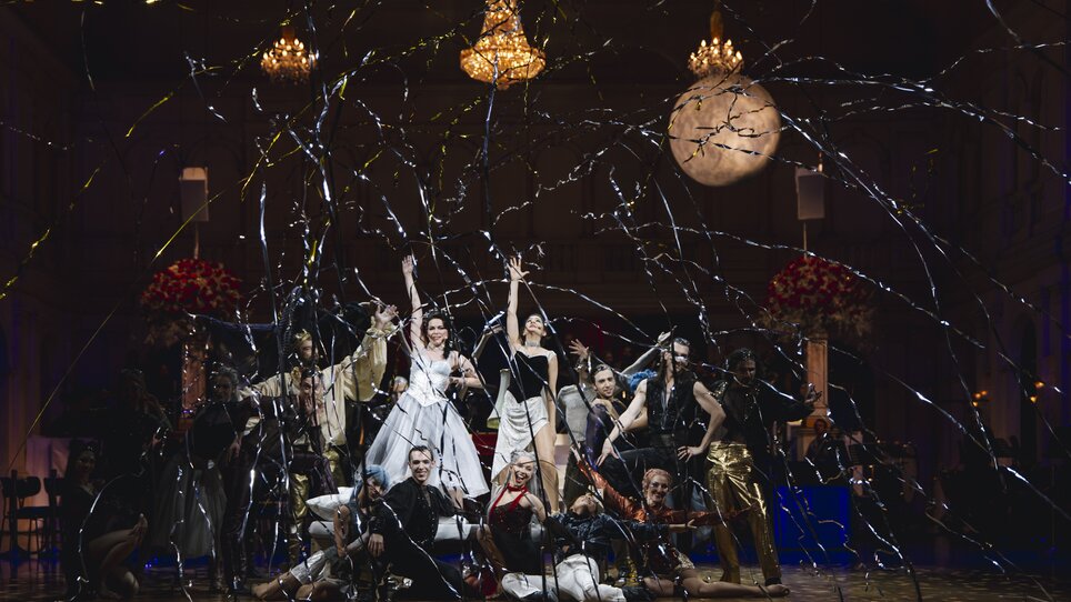 Ballerini in abiti eleganti davanti a uno sfondo festoso.