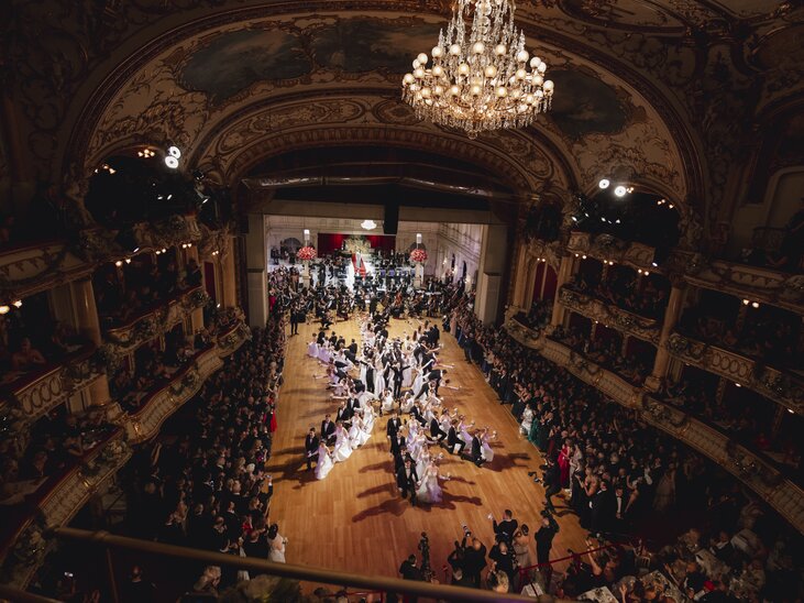 Elegantes Ballevent mit festlich gekleideten Gästen in einem prunkvollen Saal. | © Luef Light