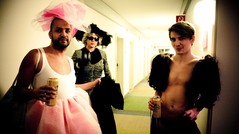 Drei Personen in auffälligen Kostümen, die in einem Flur stehen. | © Alexandra Thompson