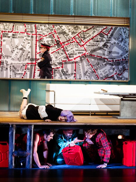 Darstellung einer Theaterszene mit Personen, die sich verstecken.