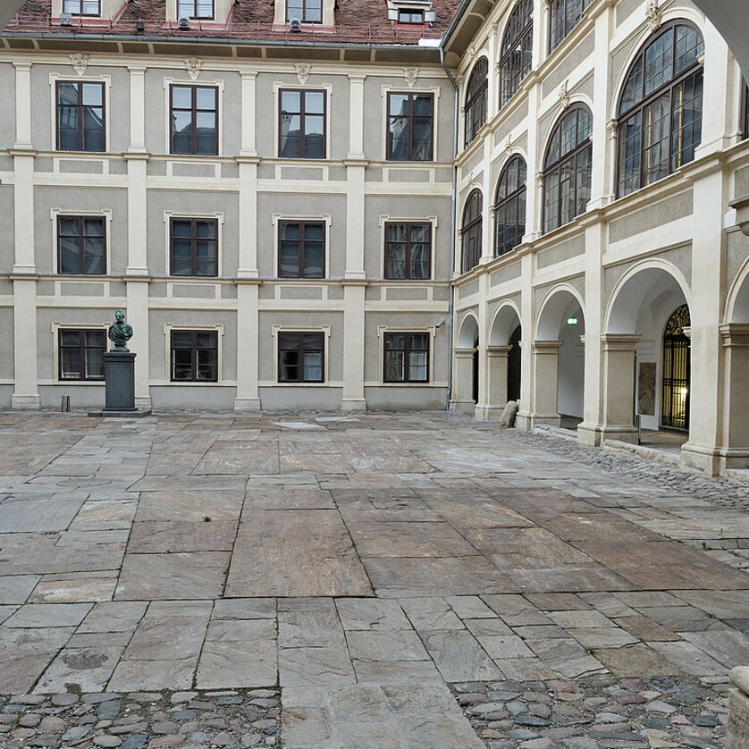 Lesliehof Joanneumsviertel | © UMJ - N. Lackner Innenhof mit Pflastersteinen, Arkadengang und Büste auf Sockel im Joanneumsviertel Graz | © UMJ - N. Lackner
