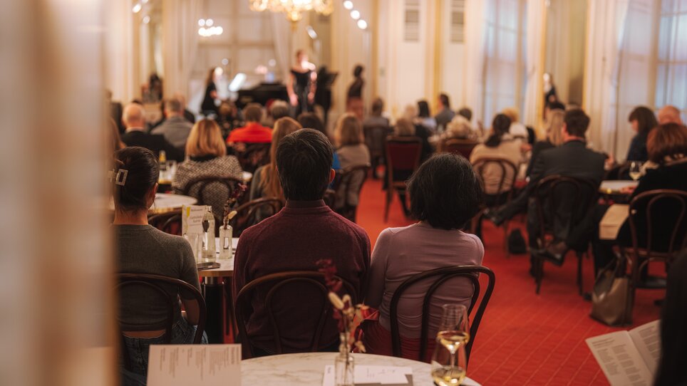 Guests enjoying a musical performance in an elegant room. | © Reithofer Media - Oper Graz