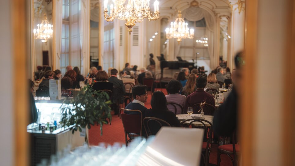 People enjoying a concert in an opulent hall with chandeliers. | © Reithofer Media - Oper Graz