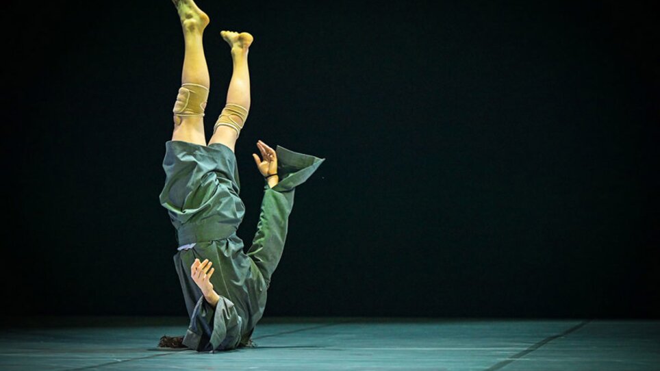 An acrobat stands upside down on stage, showcasing an impressive pose. | © Andreas J. Etter - Oper Graz