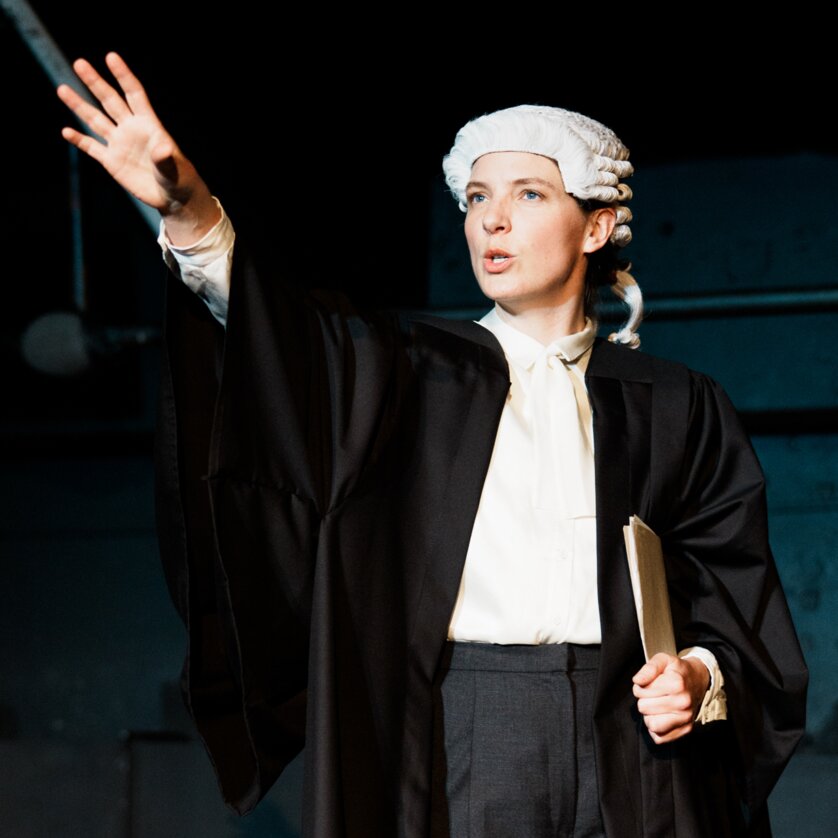 Prima Facie | © Lex Karelly Eine Person in Robe mit einer Perücke zeigt auf das Publikum. | © Lex Karelly