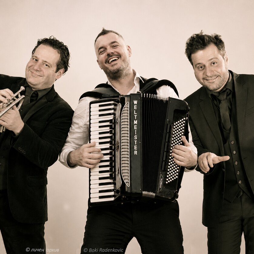 Three musicians pose together with trumpet and accordion. | © личен архив - Boki Radenkovic - IA gen