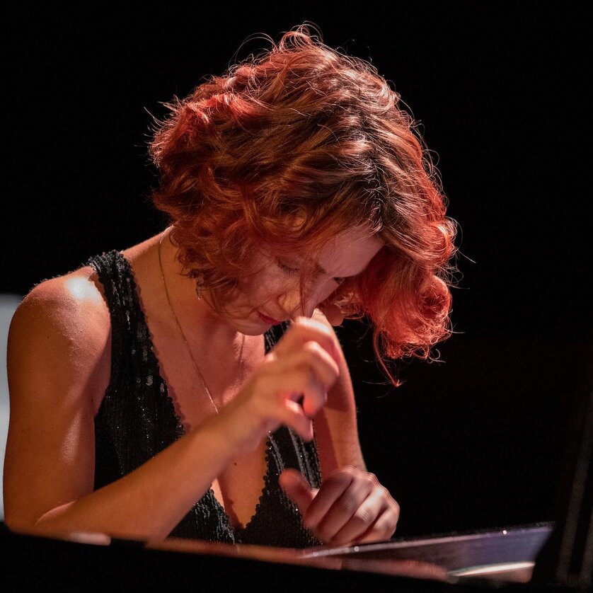 Eine Frau mit rotem Haar spielt konzentriert Klavier. | © Thom Kunz