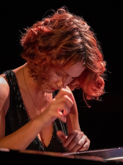Eine Frau mit rotem Haar spielt konzentriert Klavier. | © Thom Kunz