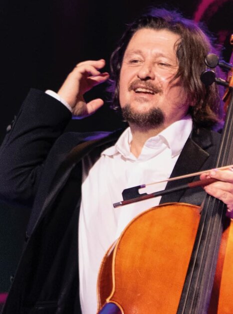 A cellist in a black suit smiles while holding his cello. | © Christan Jungwirth