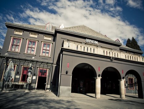 Außenansicht des Orpheum Graz bei Tag mit markanter grauer Fassade und Rundbögen. | © Spielstätten - Lupi Spuma