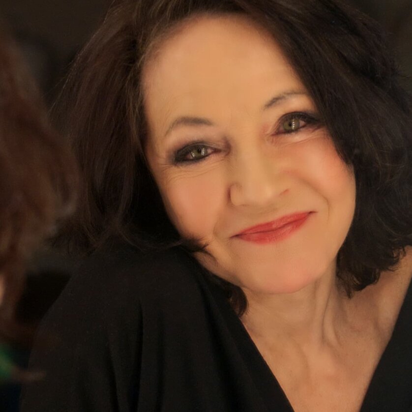 Eine Frau mit dunklen Haaren lächelt in den Spiegel. | © Gabriela Brandenstein