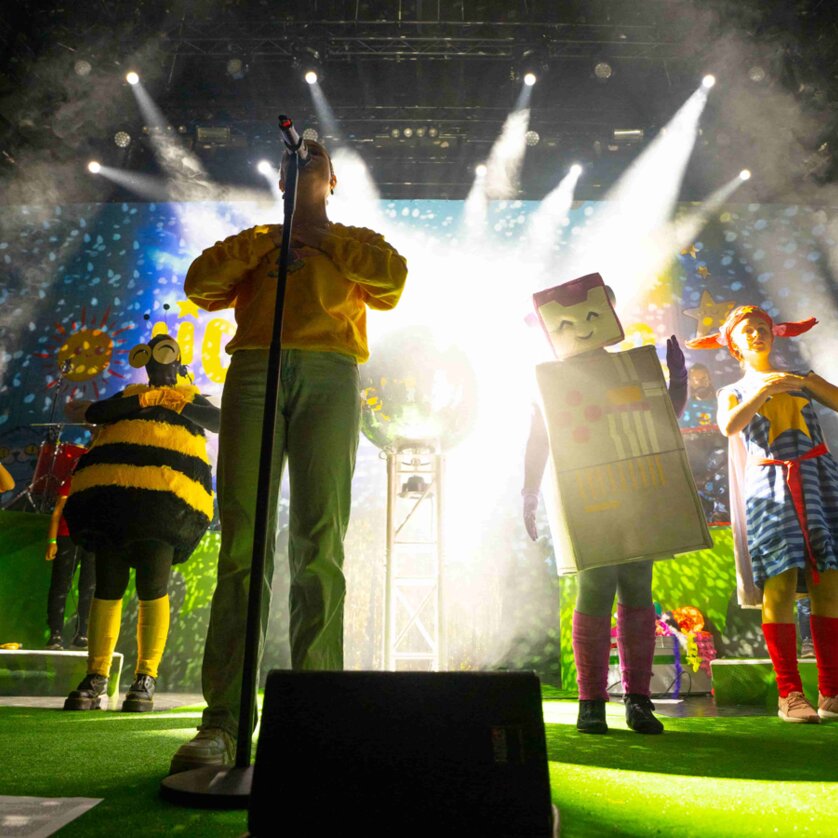 Kinder in Kostümen treten auf einer bunten Bühne auf. | © Lichterkinder