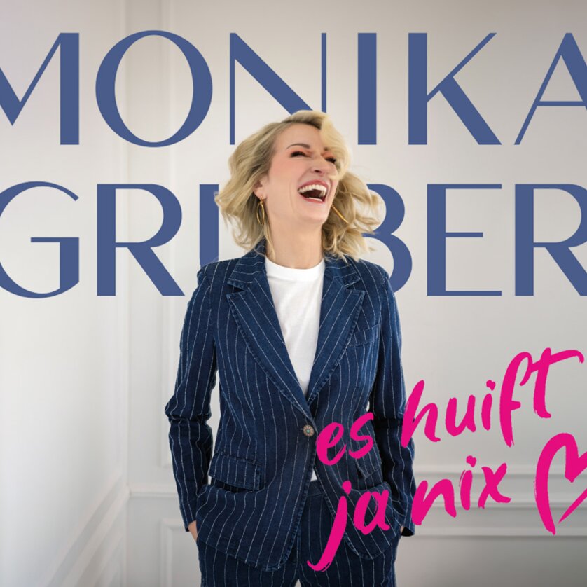 Monika Gruber lacht in einem blauen Streifenanzug. | © Starupphoto