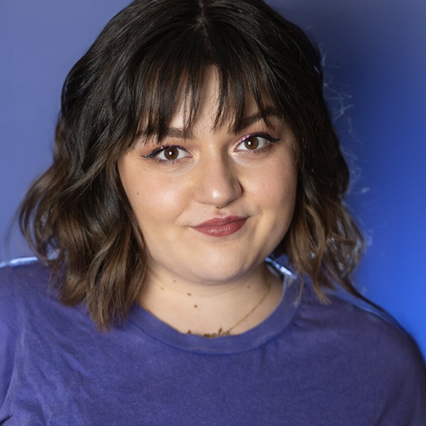 Junge Frau mit lockigem Haar in einem violetten Shirt vor blauem Hintergrund. | © Teresa Reichl