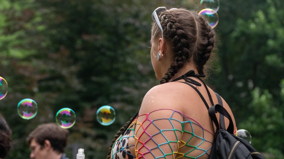 Young woman with braids and net top, surrounded by soap bubbles. | © Maya Hanl