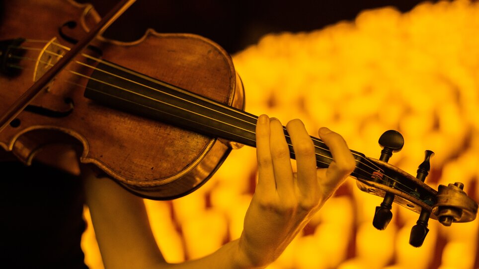 Close-up of a violin played by hand in warm candlelight | © Fever
