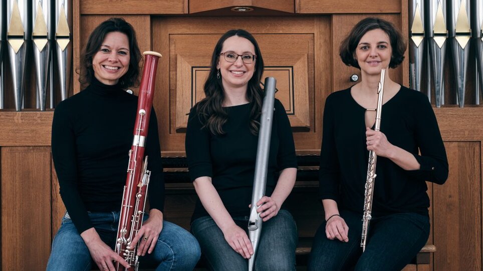 Drei Musikerinnen, die Flöte, Fagott und Querflöte halten, vor einer Orgel. | © Triolog - Andy Moser