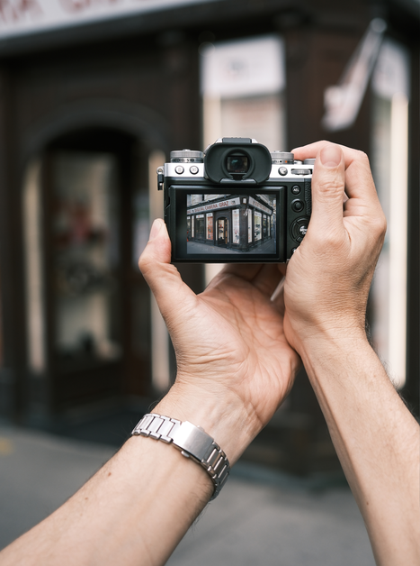Eine Person fotografiert einen Blick auf ein Ladenschild mit einer Kamera. | © Maria Alberer