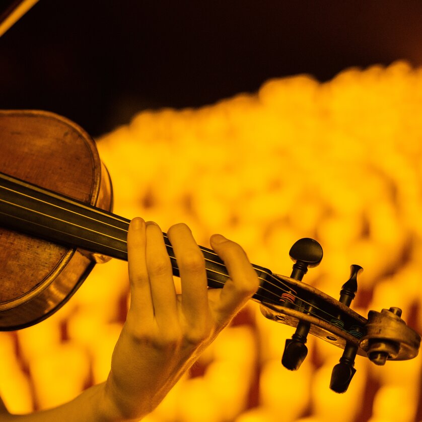 Close-up of a violin played by hand in warm candlelight | © Fever