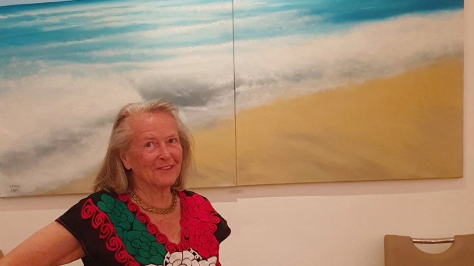 Eine Frau vor einem blauen Meer-Gemälde in einer Galerie. | © Beatrix Prinz