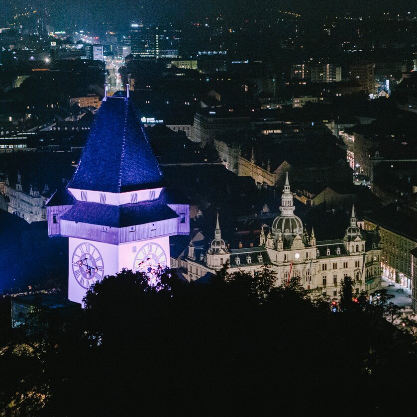Nachtansicht von Graz mit Grazer Uhrturm | © Sebastian Reiser Beleuchtete Stadt Graz bei Nacht mit dem Grazer Uhrturm im Vordergrund. | © Sebastian Reiser