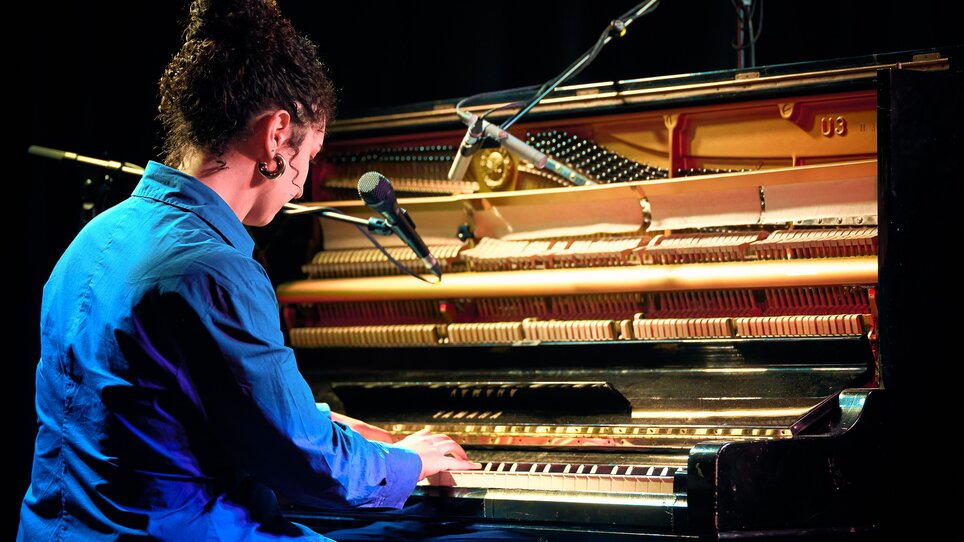 A pianist playing at a piano with a microphone in the background. | © Kuro Simon