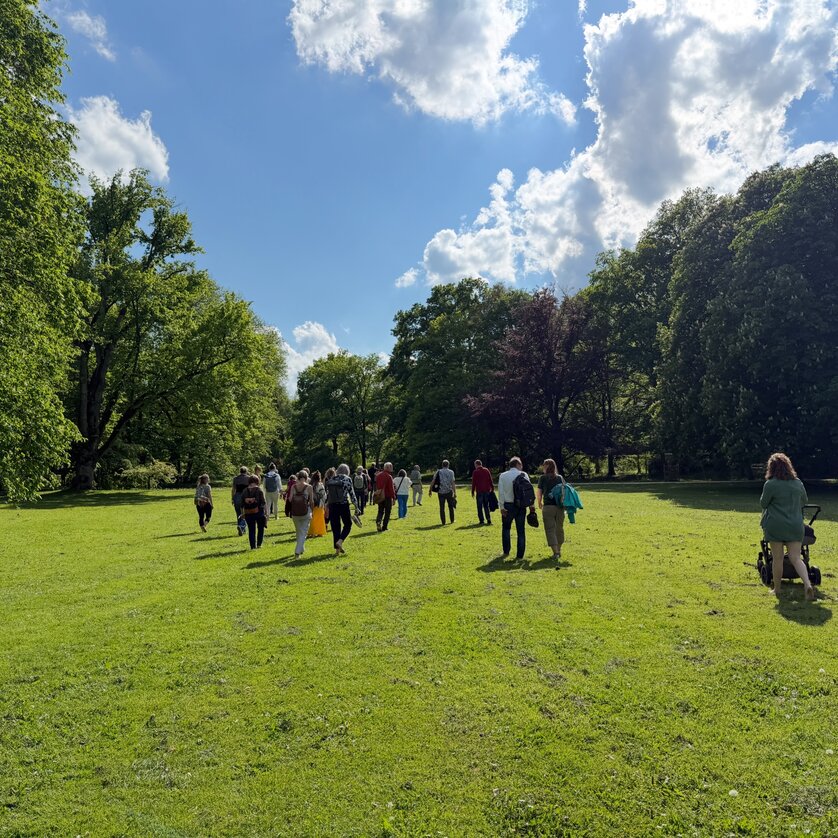 Gruppe von Personen, die durch eine grüne Parklandschaft geht. | © Toby Mayra
