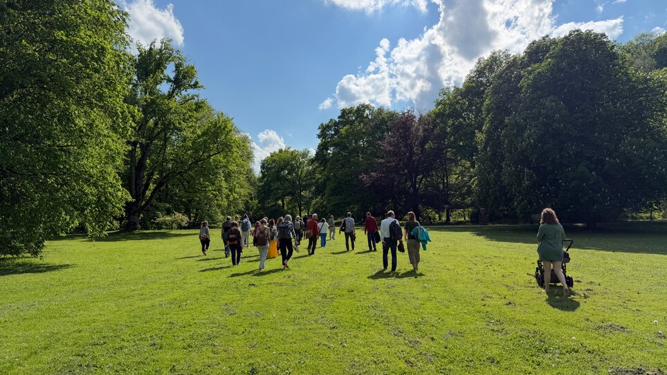 Gruppe von Personen, die durch eine grüne Parklandschaft geht. | © Toby Mayra